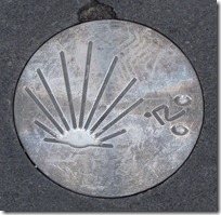 A marker in the street that indicates this path is a part of The Way of St. James.
